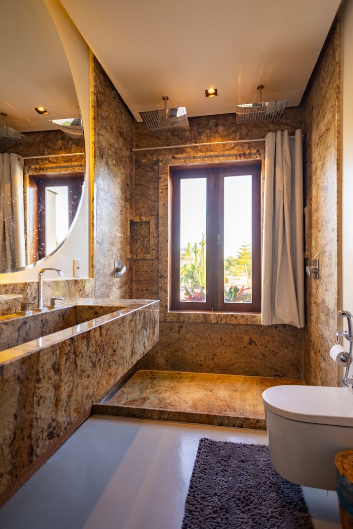 about-01 Luxurious bathroom featuring stone walls and modern fixtures with natural light.